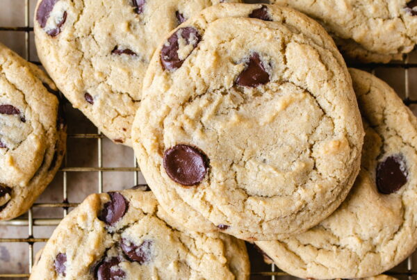 Chocolate chip cookies cooling on a wire rack in a commercial bakery, chips visible on the surface